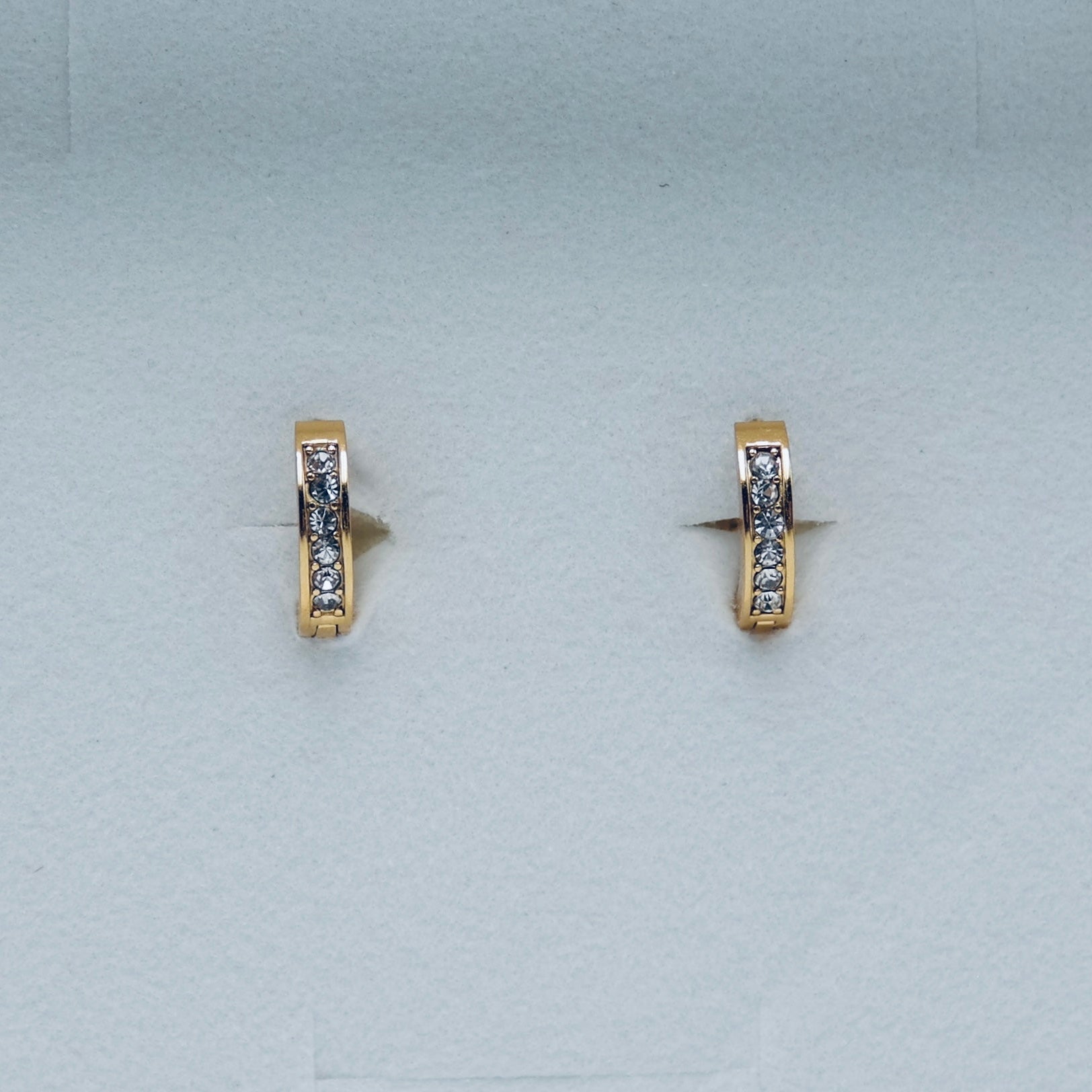 Pair of gold hoop earrings with embedded stones on a light gray background. Water proof Jewellery. Gym jewellery